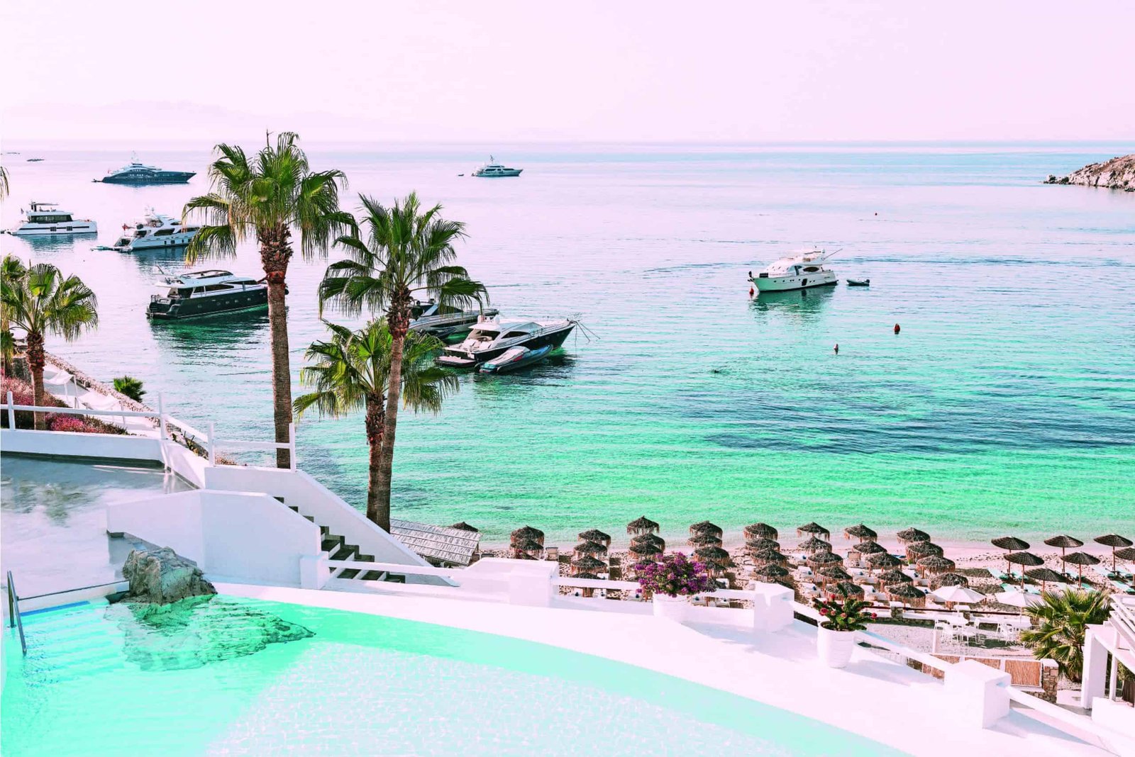 A legendary pool overlooking a Greek beach with boats in the distance.