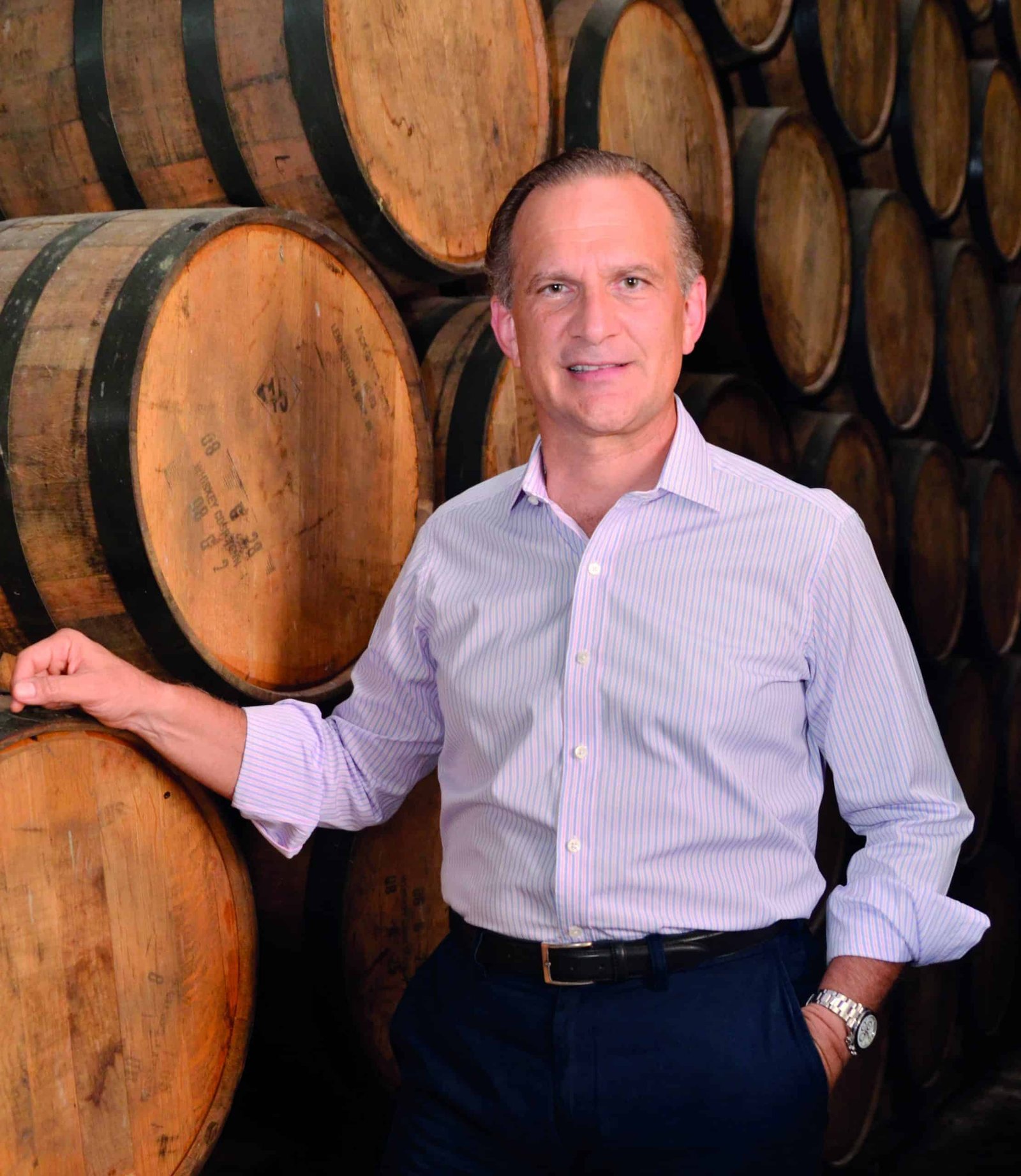 A man standing in front of wooden barrels full of rum.
