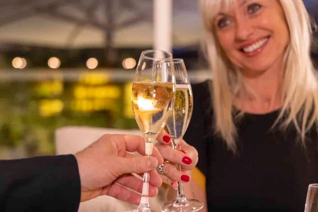 A woman and man celebrating with glasses of champagne at a fancy restaurant.