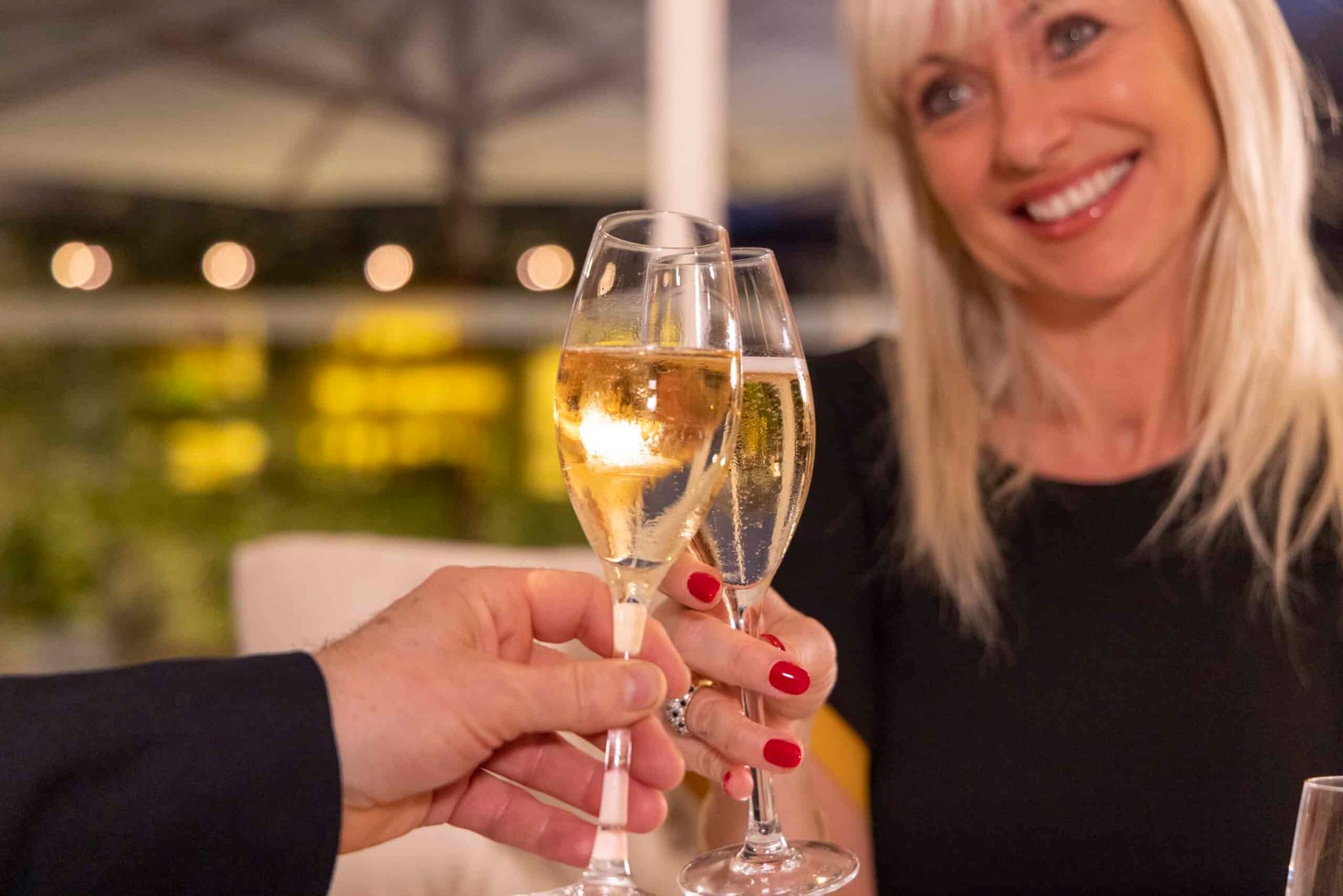 A woman and man celebrating with glasses of champagne at a fancy restaurant.