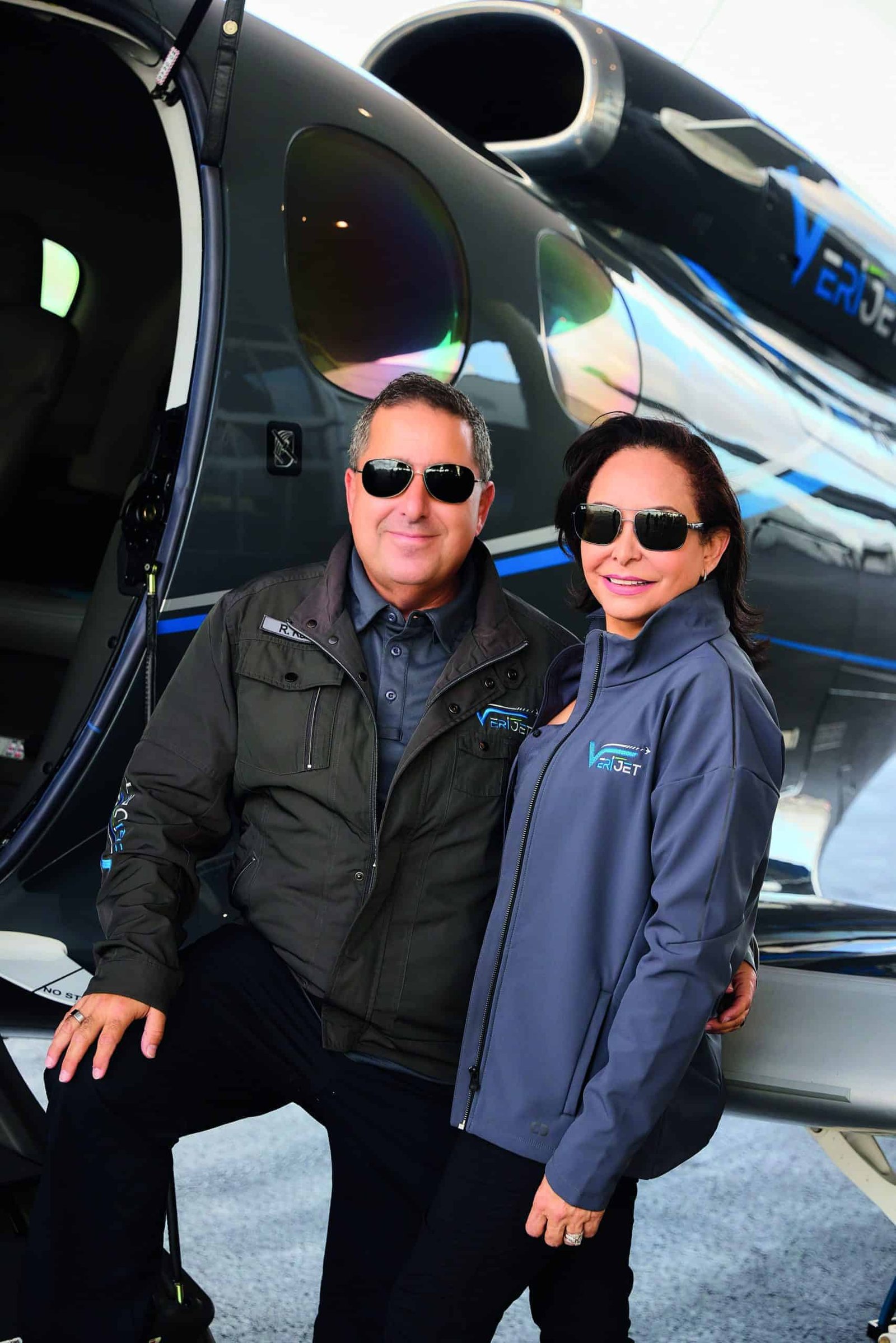 A couple jetting off into the future, posing in front of a plane.