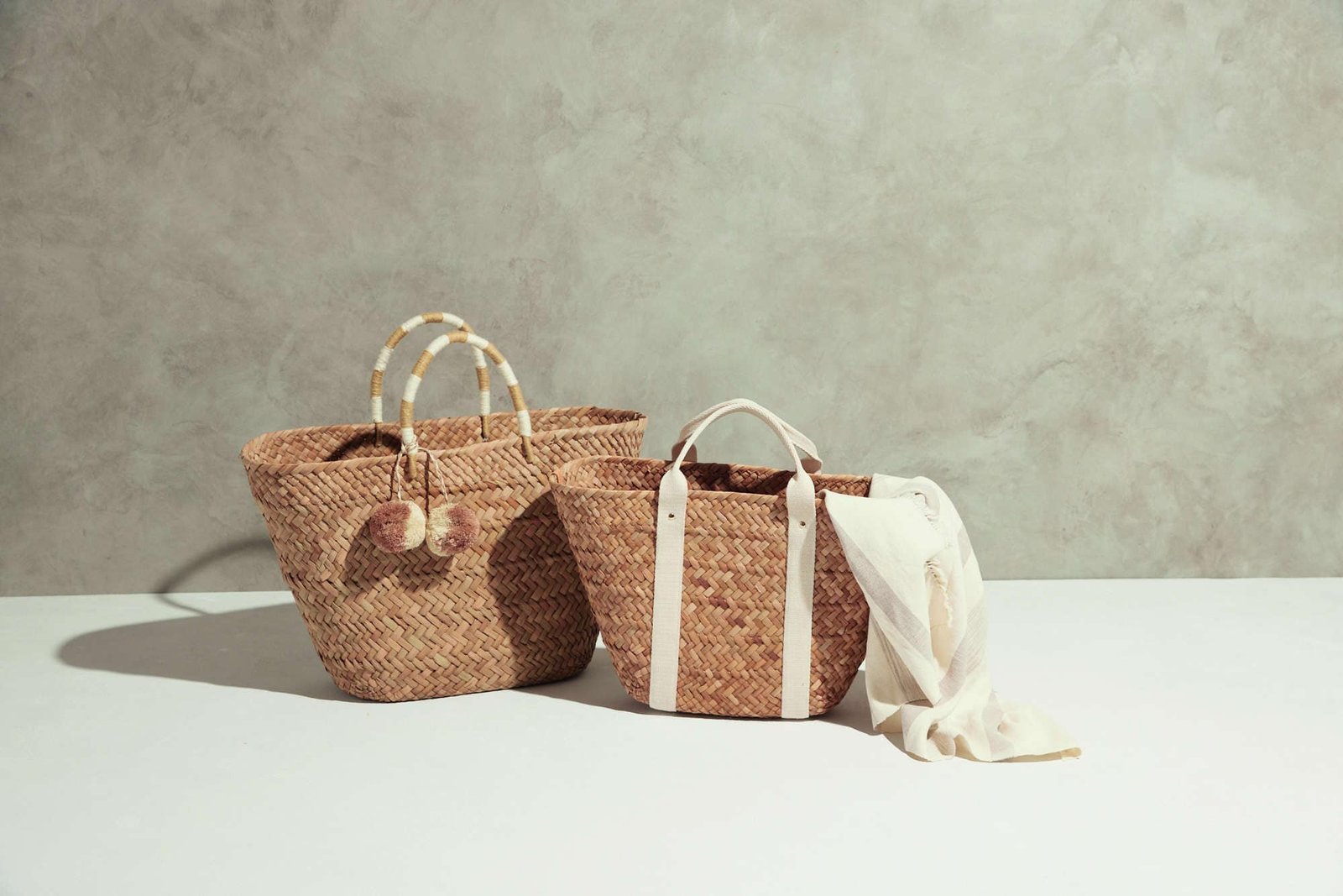Two natural rattan baskets on a table, designed side by side.