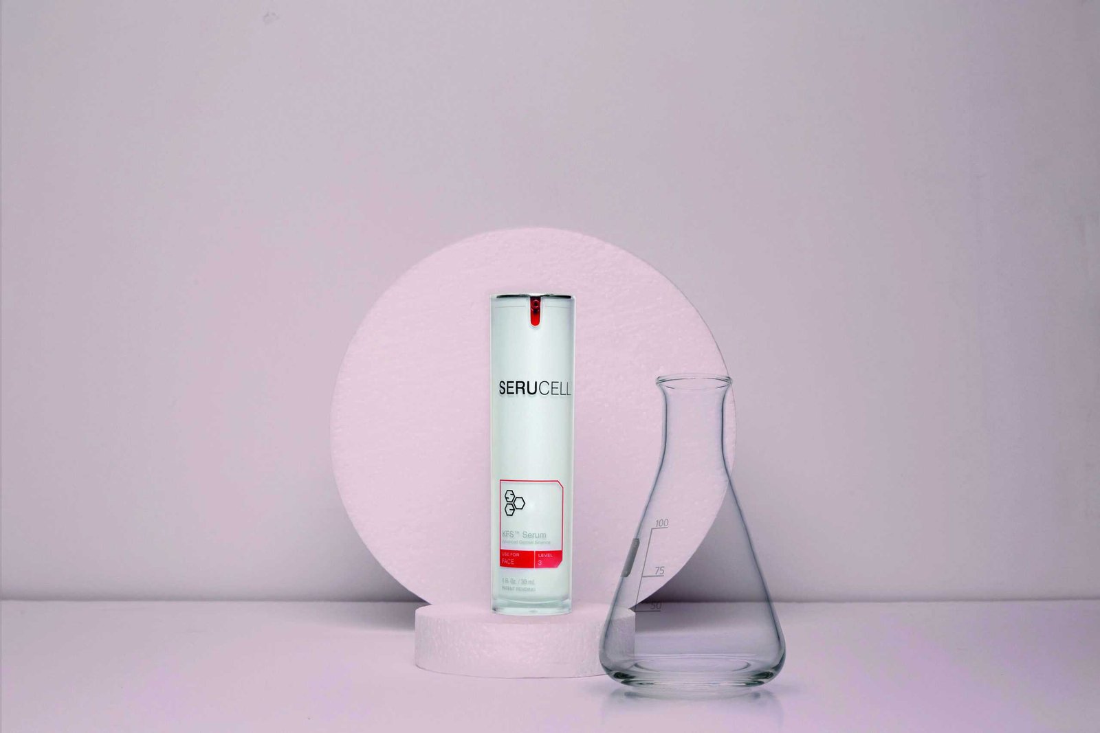 A bottle and a glass on a level pink background.