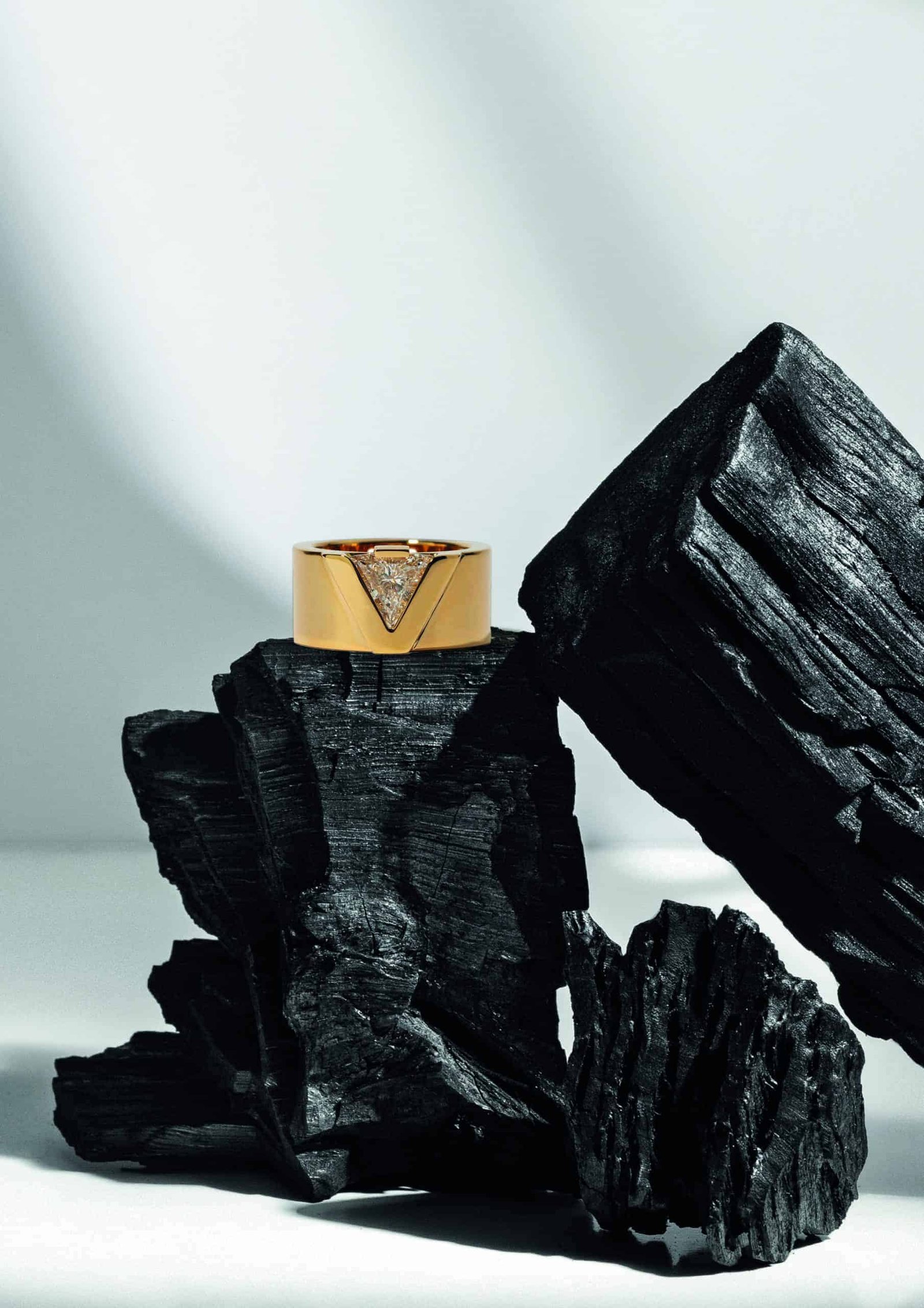 An opulent gold ring sits on top of black rocks, representing a tiny glimpse into the vastness of the universe.