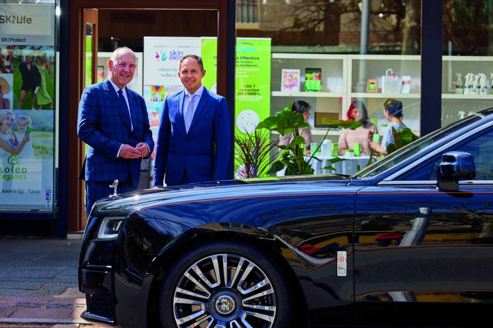 Two people standing in front of a Rolls Royce car.