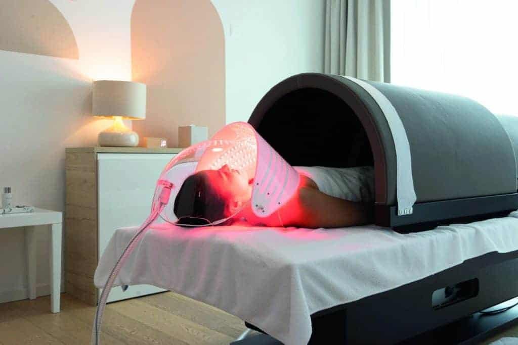 A Swiss woman lying on a bed in a room with a medical machine.