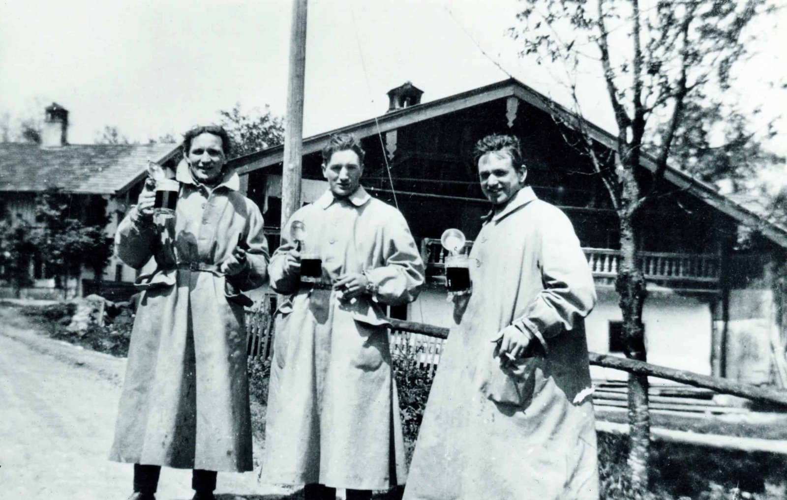 Three men in coats standing on a century-old dirt road.