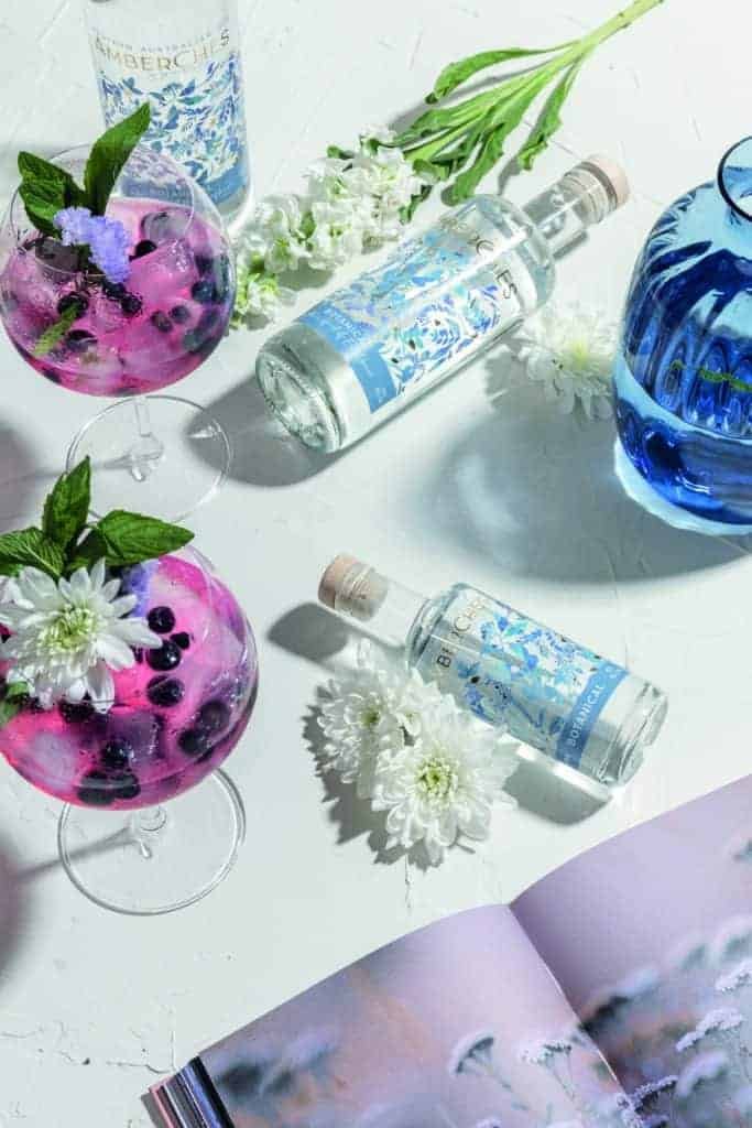 A bottle of gin and flowers on a table.