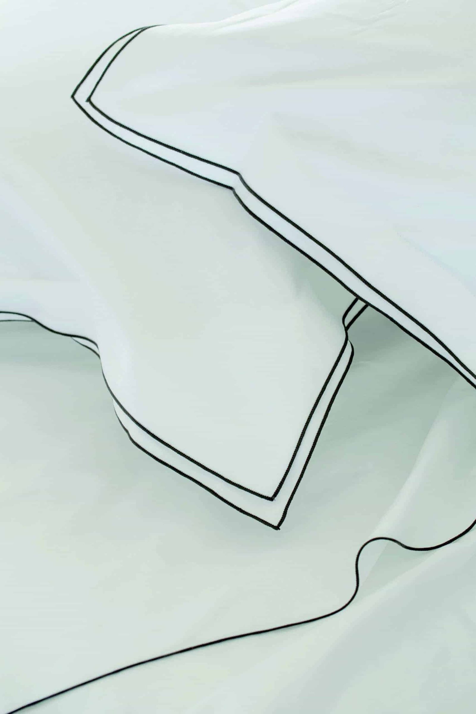 A white sheet with black piping, perfect for the best bedding.