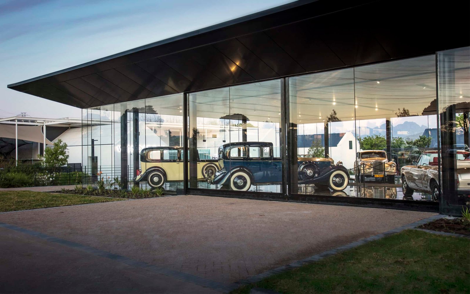 A destination featuring a glass building showcasing a plethora of old cars on display.