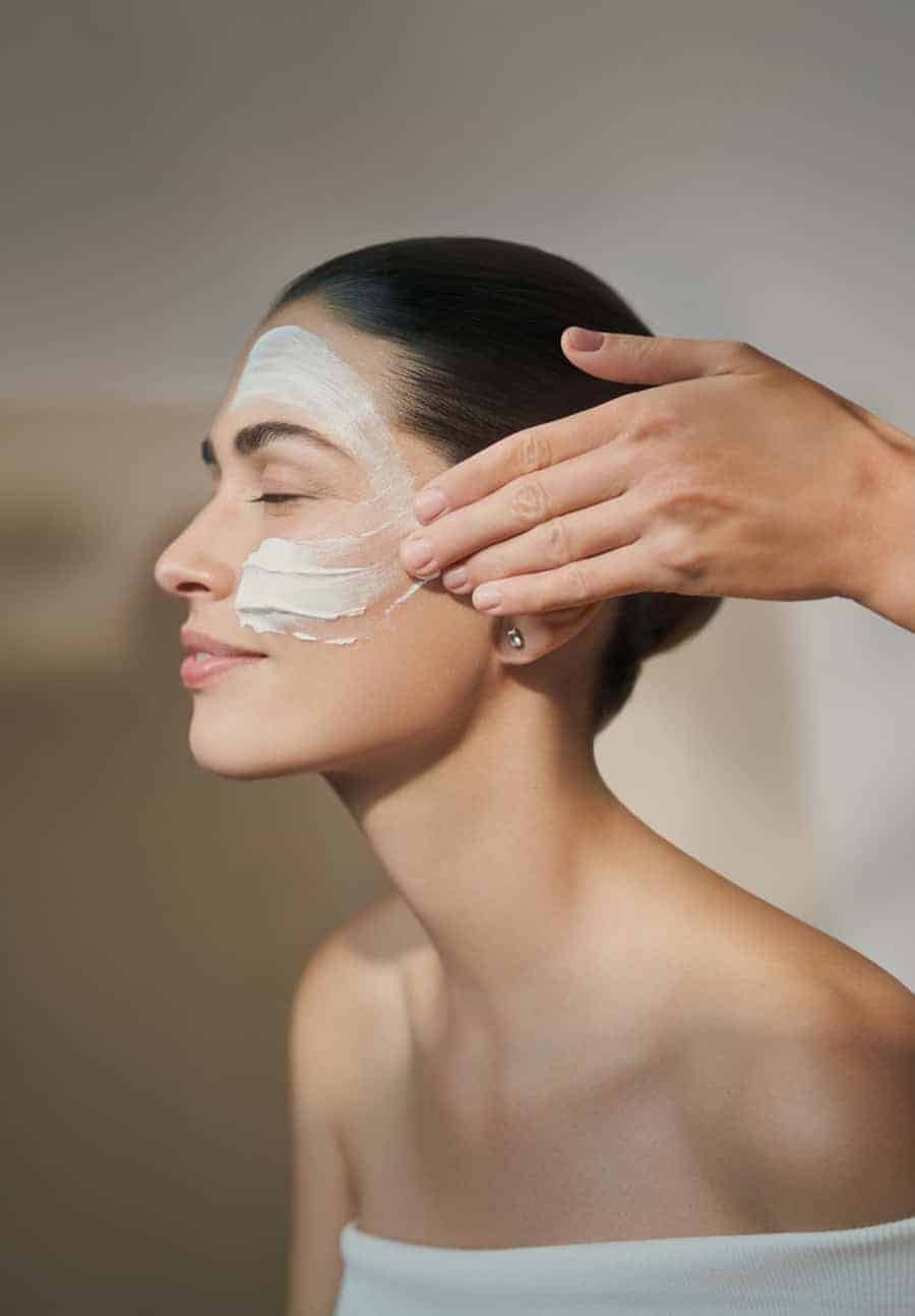 A woman experiencing a sense of wellbeing while getting a facial mask at a spa.