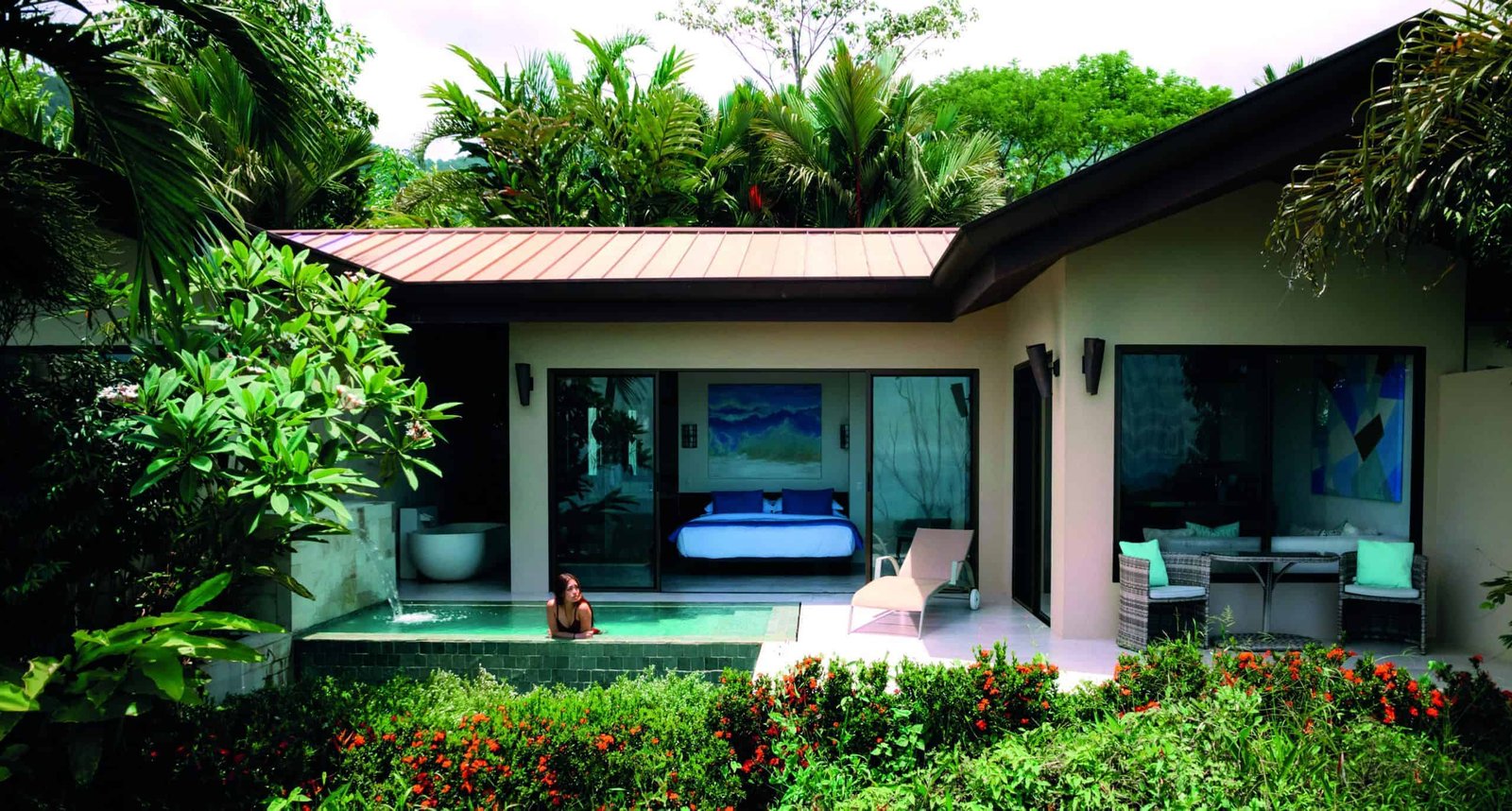 A naturally stunning house with a pool in the middle of a tropical garden.