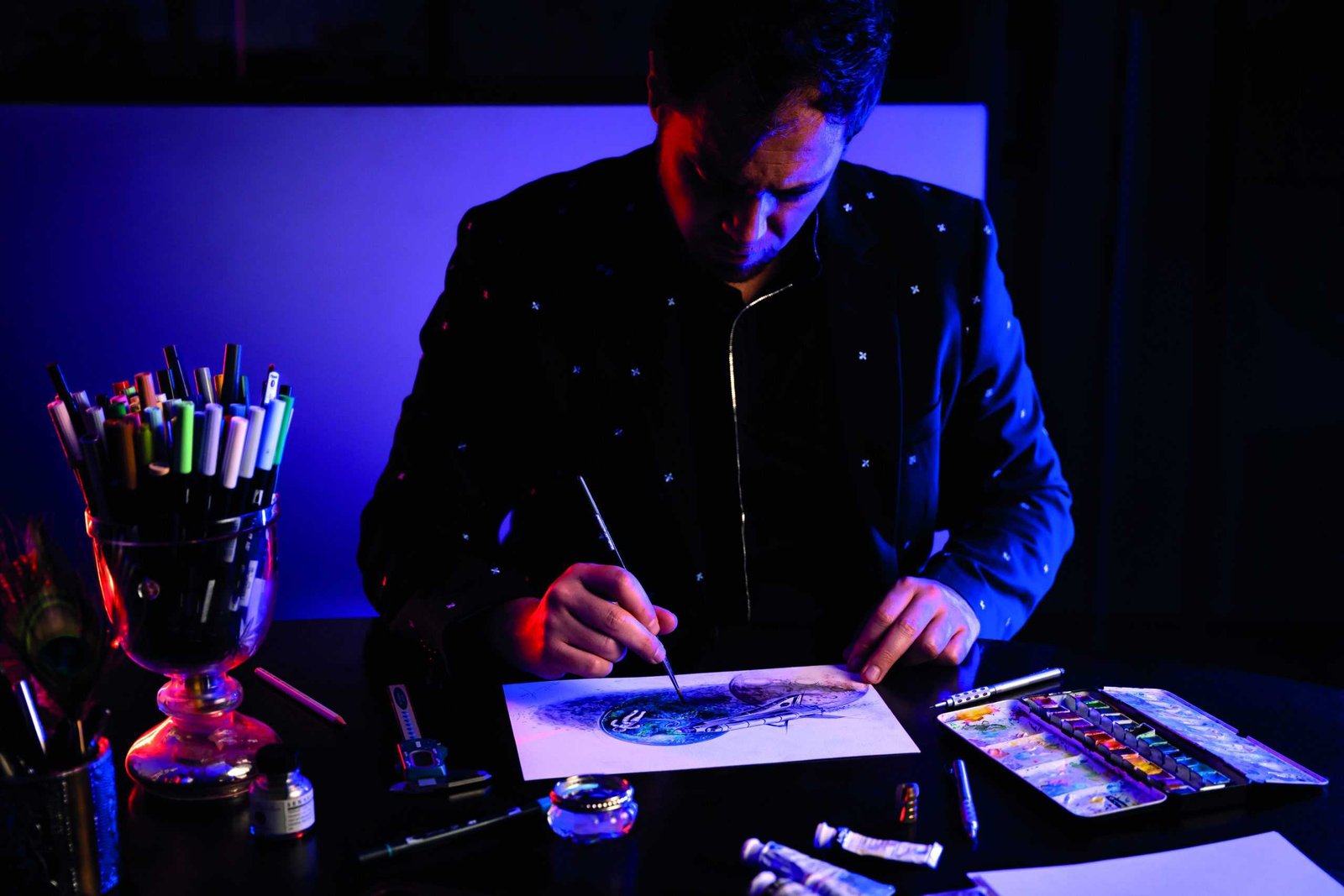 A man capturing a life moment as he sits at a table drawing a picture.