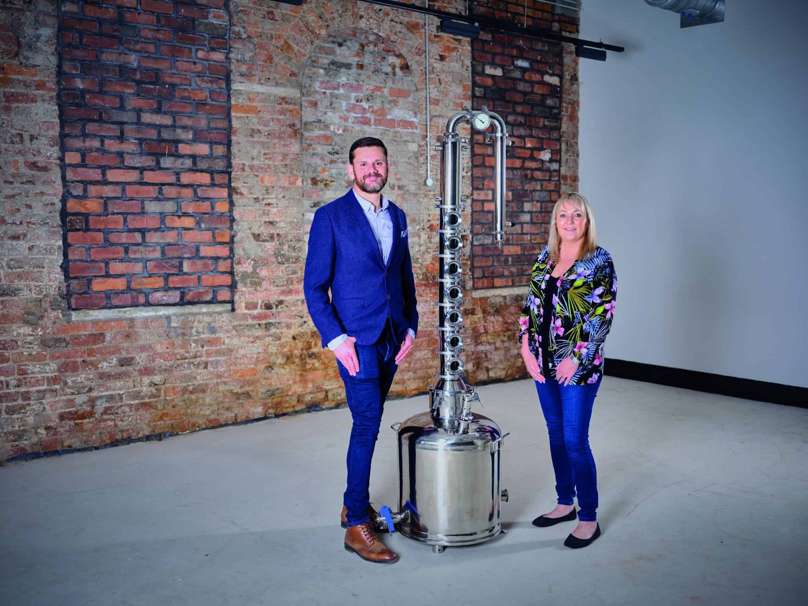 A man and woman forging ahead next to a large metal pot.