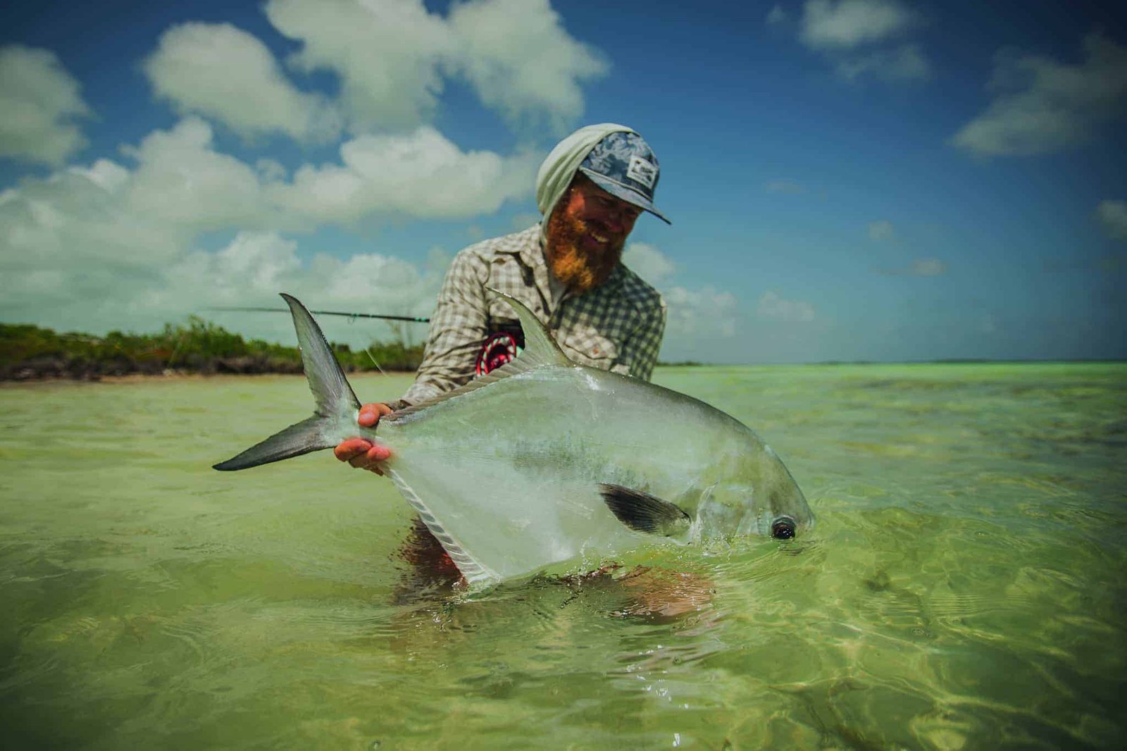 A man catches a large fish in the water.