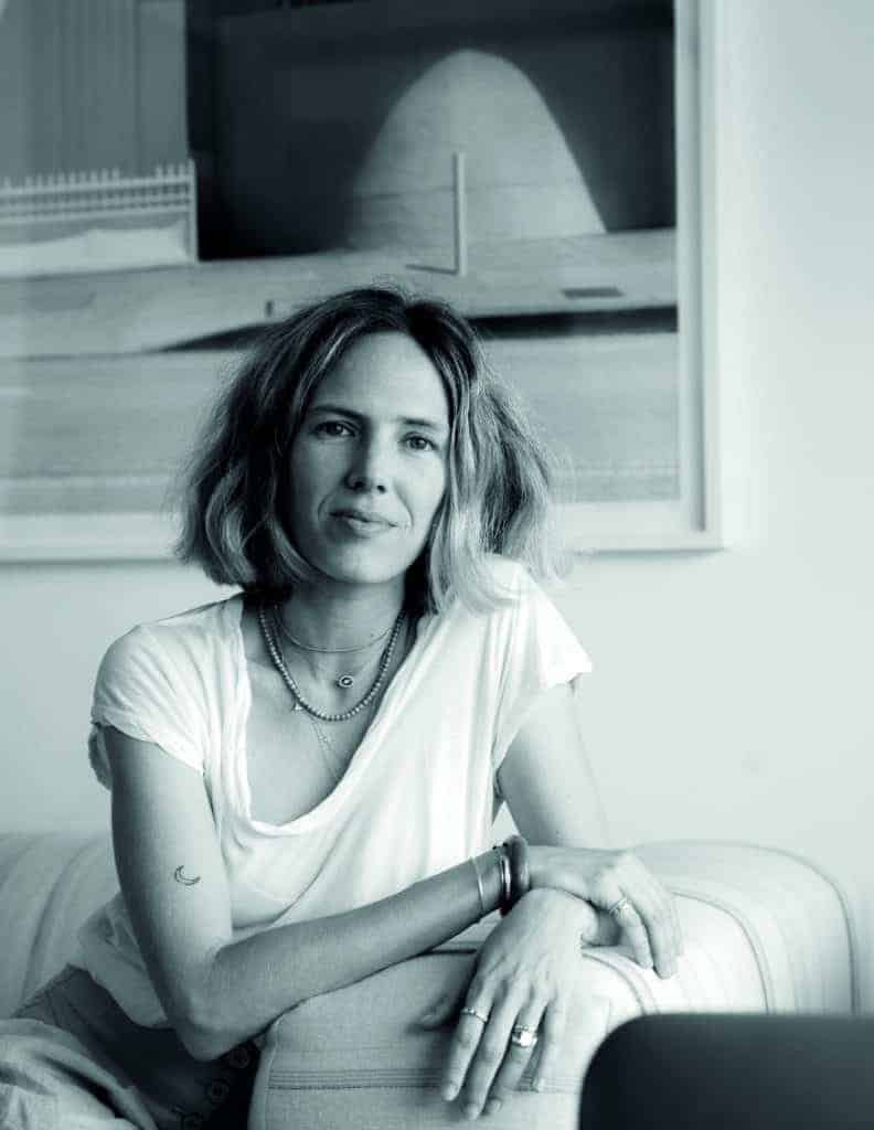 A classic black and white photo of a woman sitting on a couch with a subtle twist.