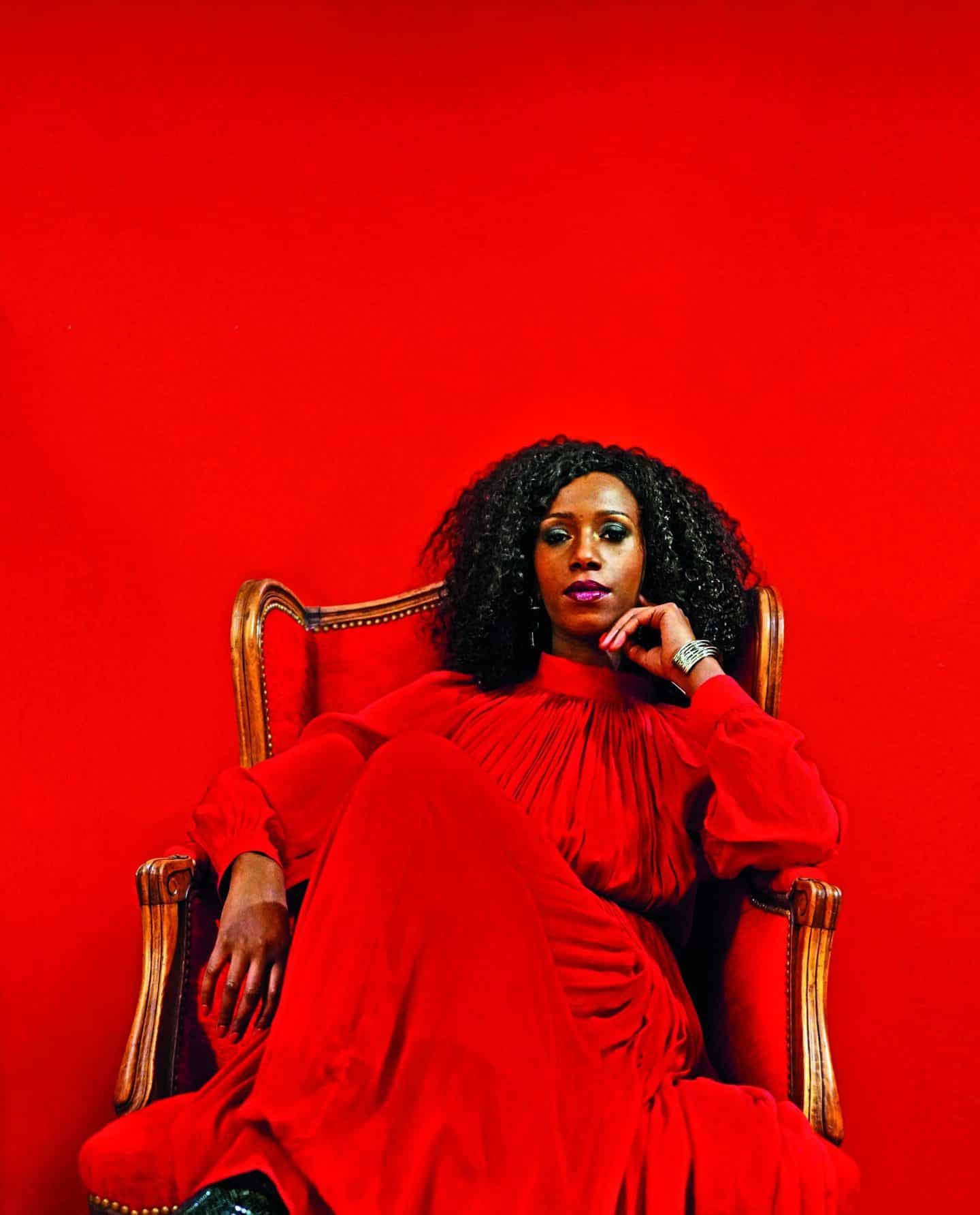 A woman in a red dress sitting in a chair showcasing skin deep allure.