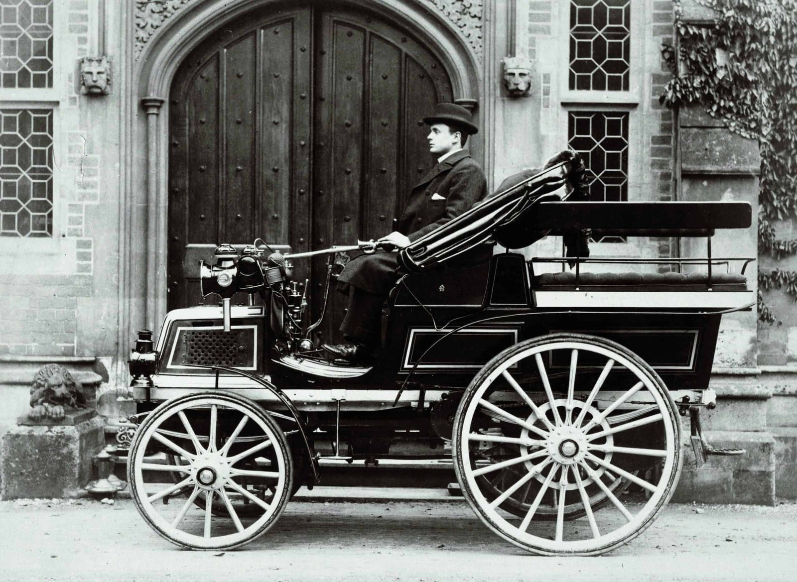 An old photo of a man sitting in a carriage shaped like a wind.