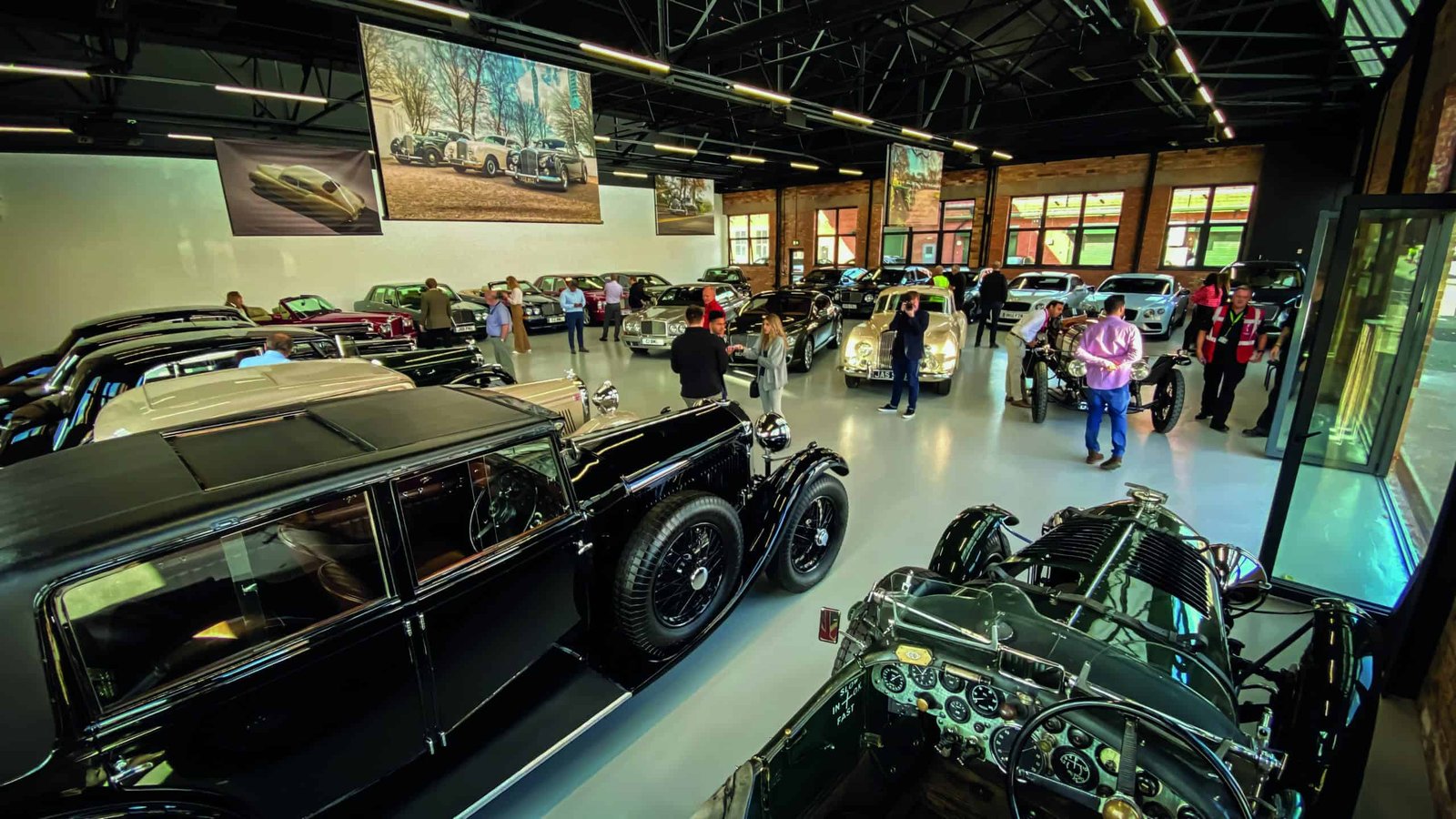 A group of people looking at antique cars in a museum.
