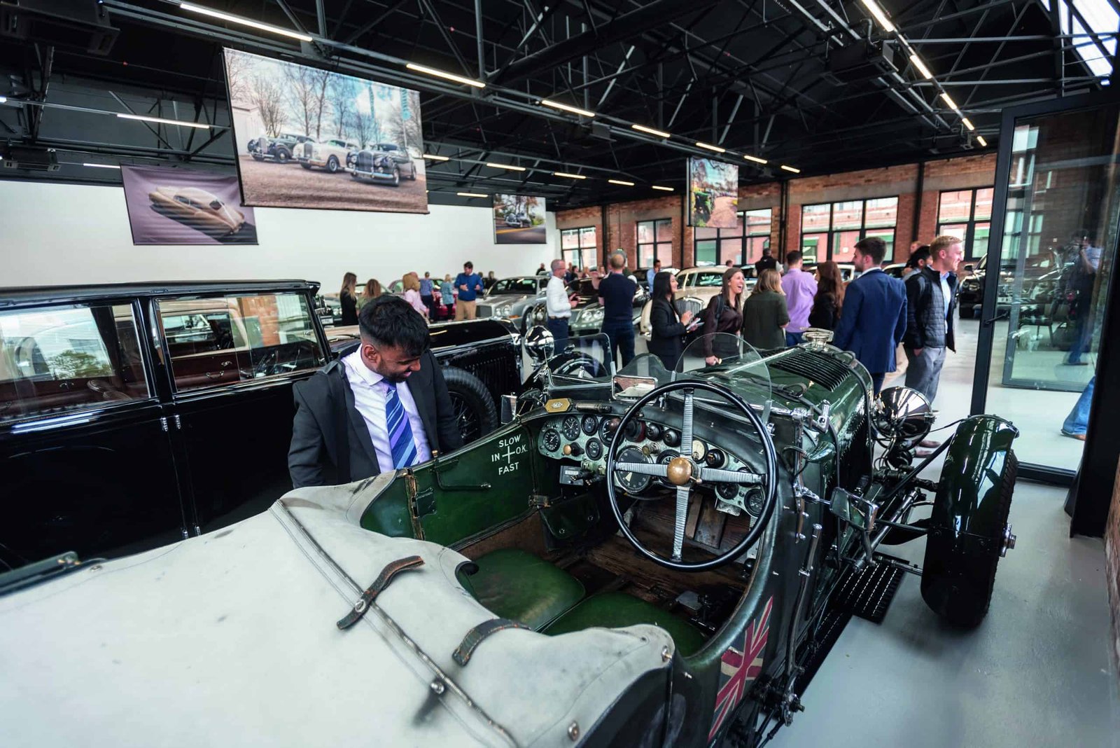 A group of people looking at antique cars in a museum.