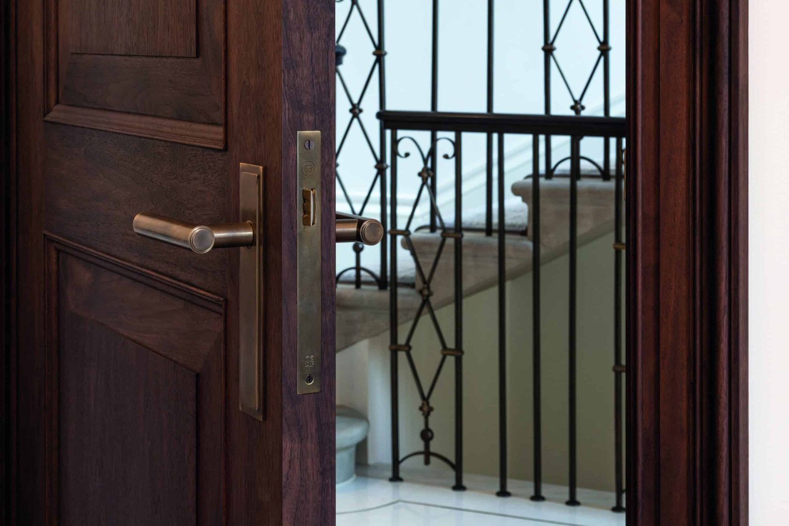 A wooden door with a bold wrought iron handle.