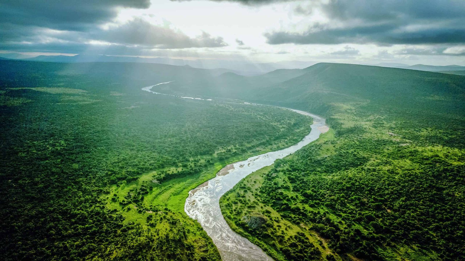 An aerial view of an authentic river in a green valley in Africa.