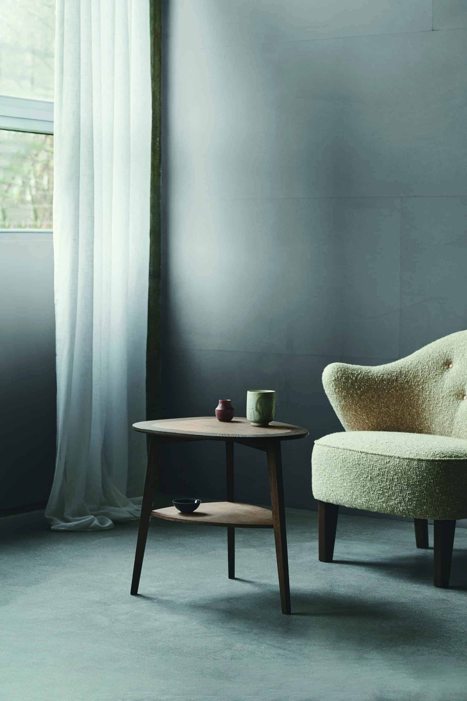 A vintage chair and handcrafted table in a sunlit room with a large window.