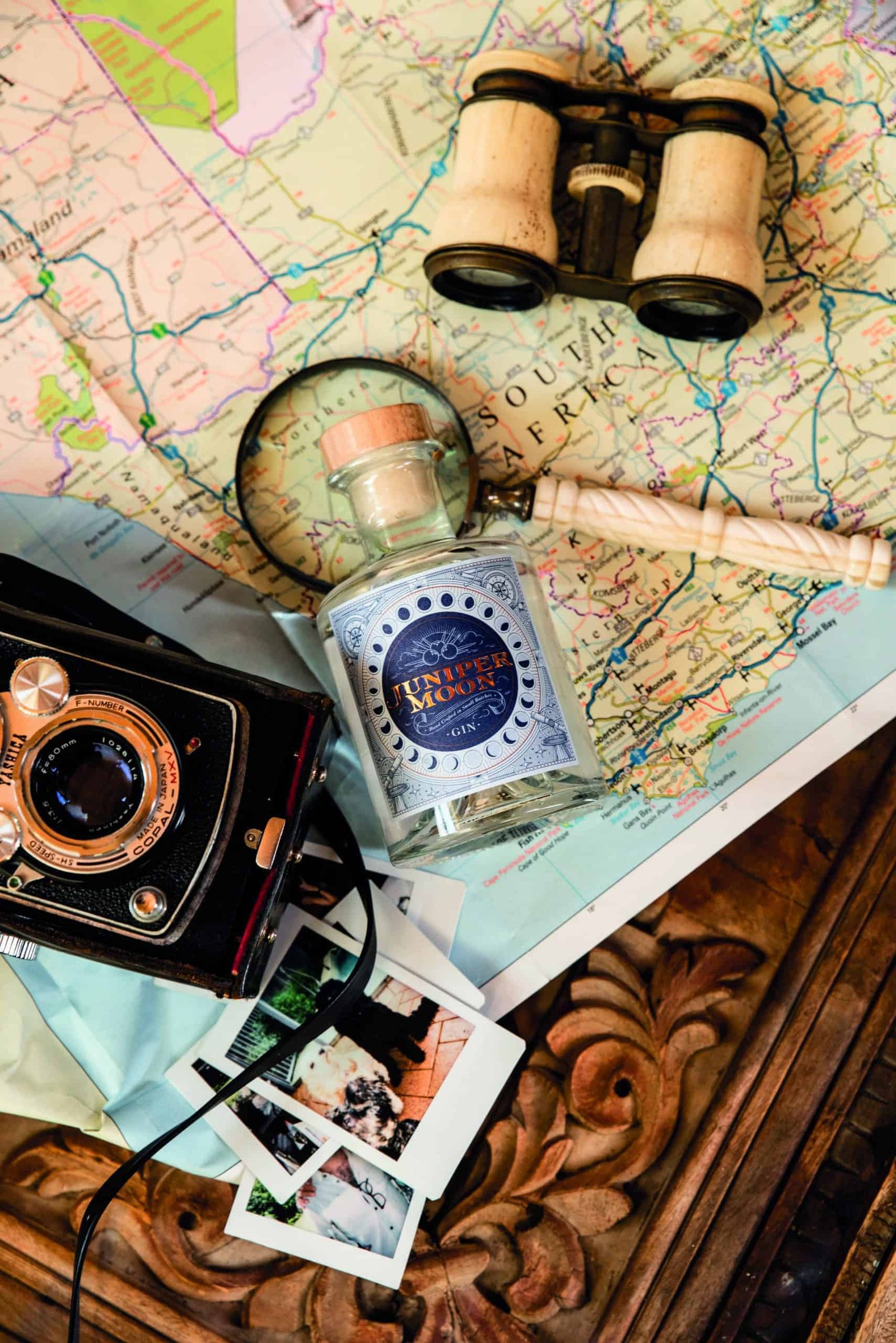 A vintage camera, binoculars, and a map on a table ready for a journey.