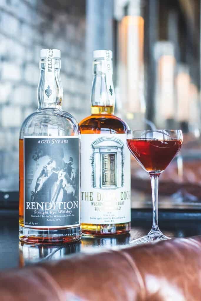 A bottle of bourbon sits next to a glass of wine, inviting a journey into natural flavors.