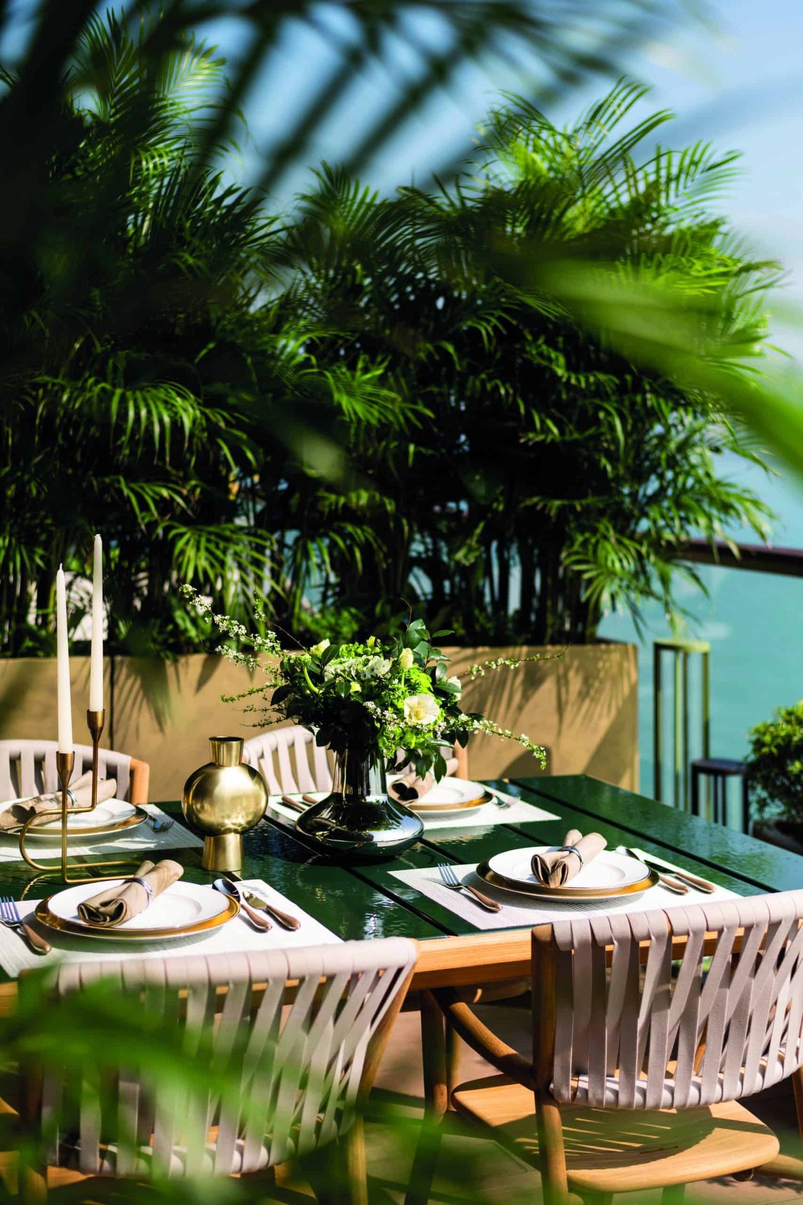 A stylish table is set on a balcony overlooking the ocean.
