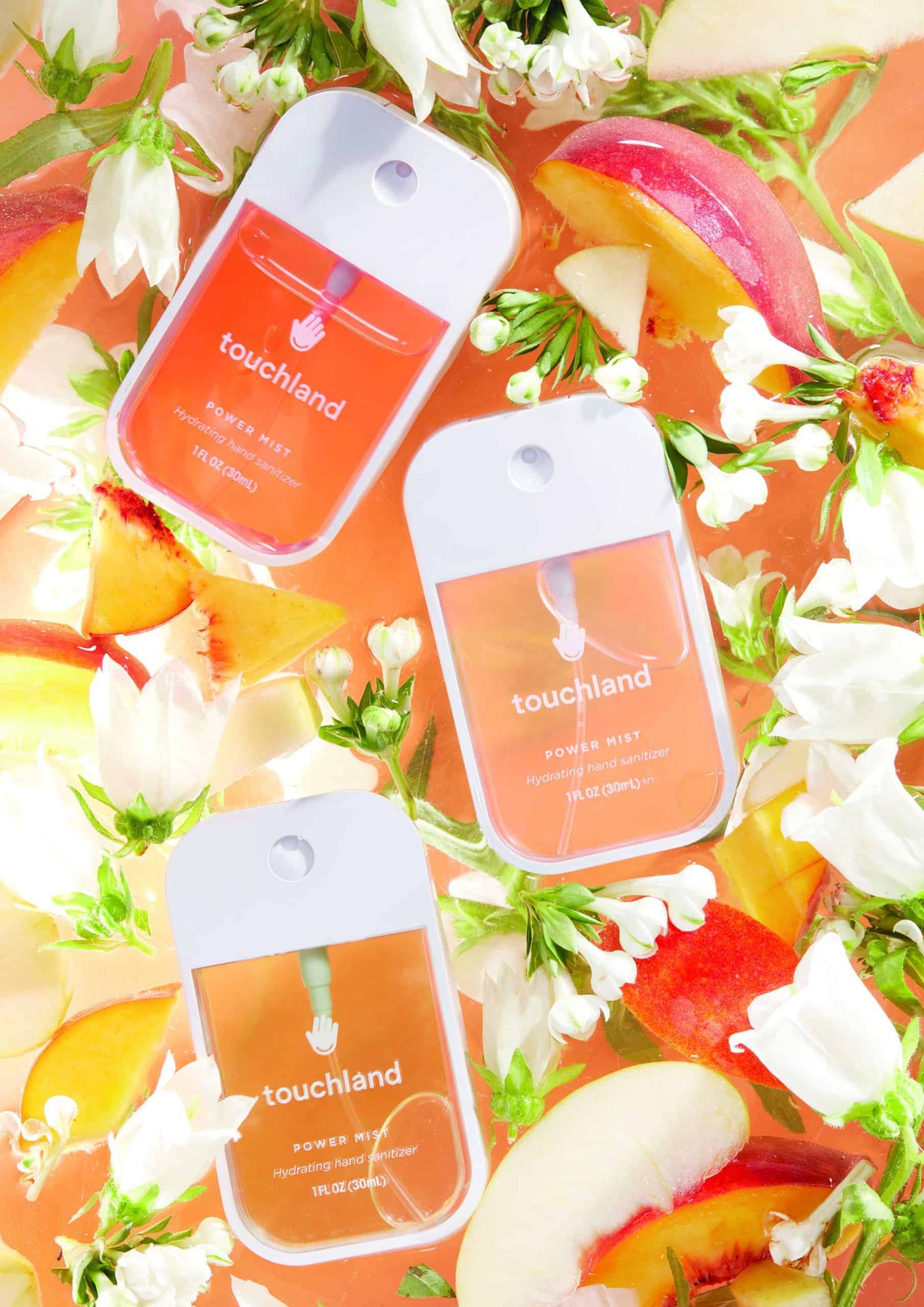A hands-on approach to a bunch of peach scented products surrounded by flowers.