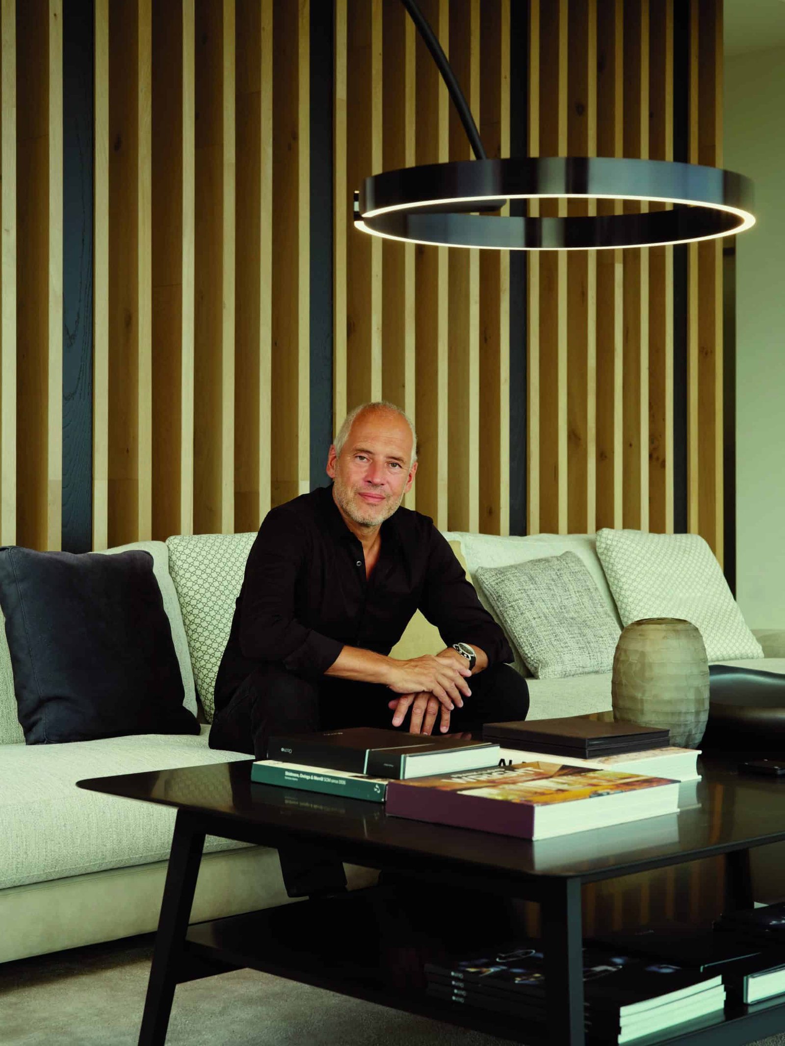 A man sitting on a couch in a well-lit living room.