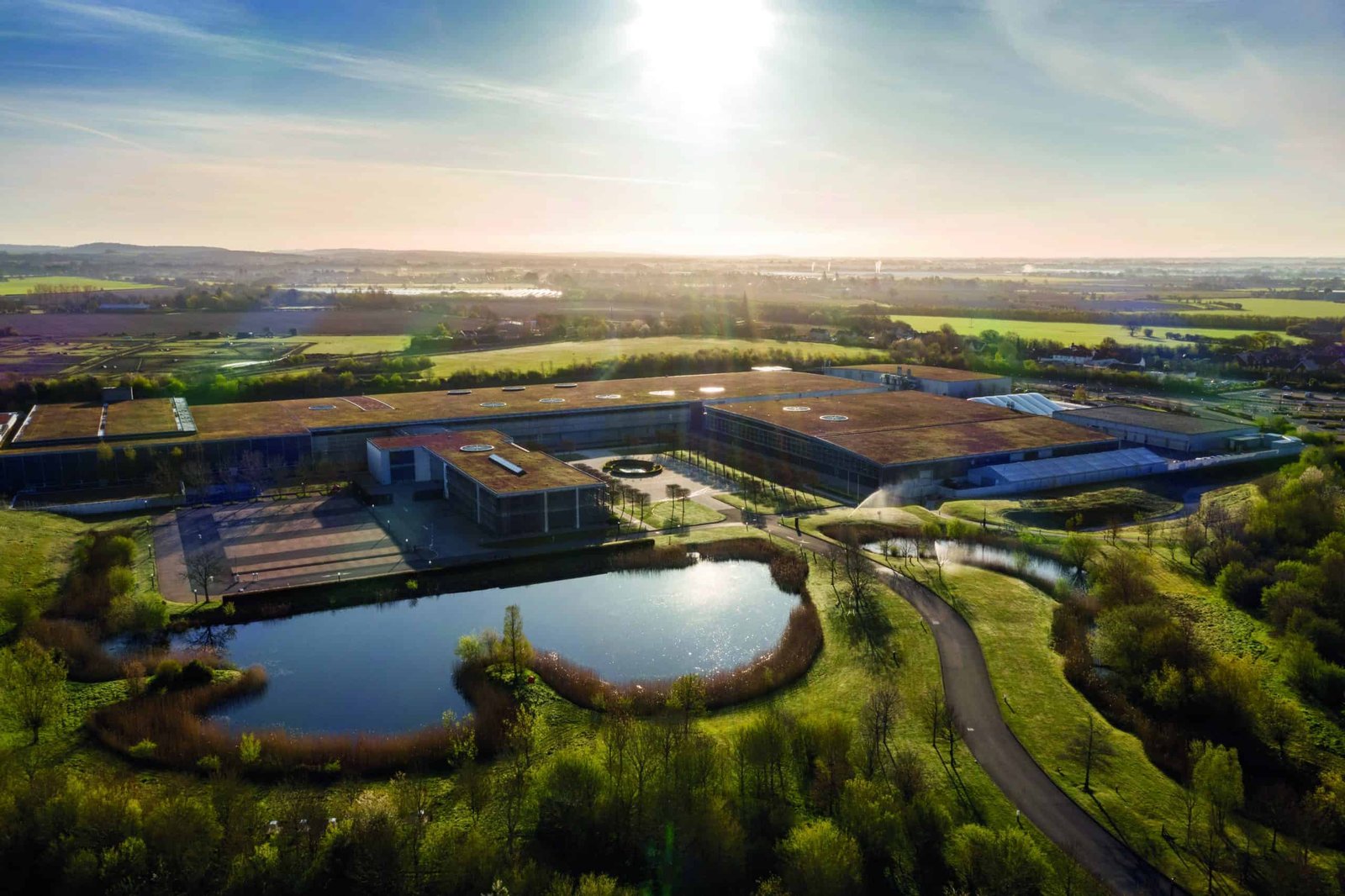 An aerial view of a large building with a pond in the background.