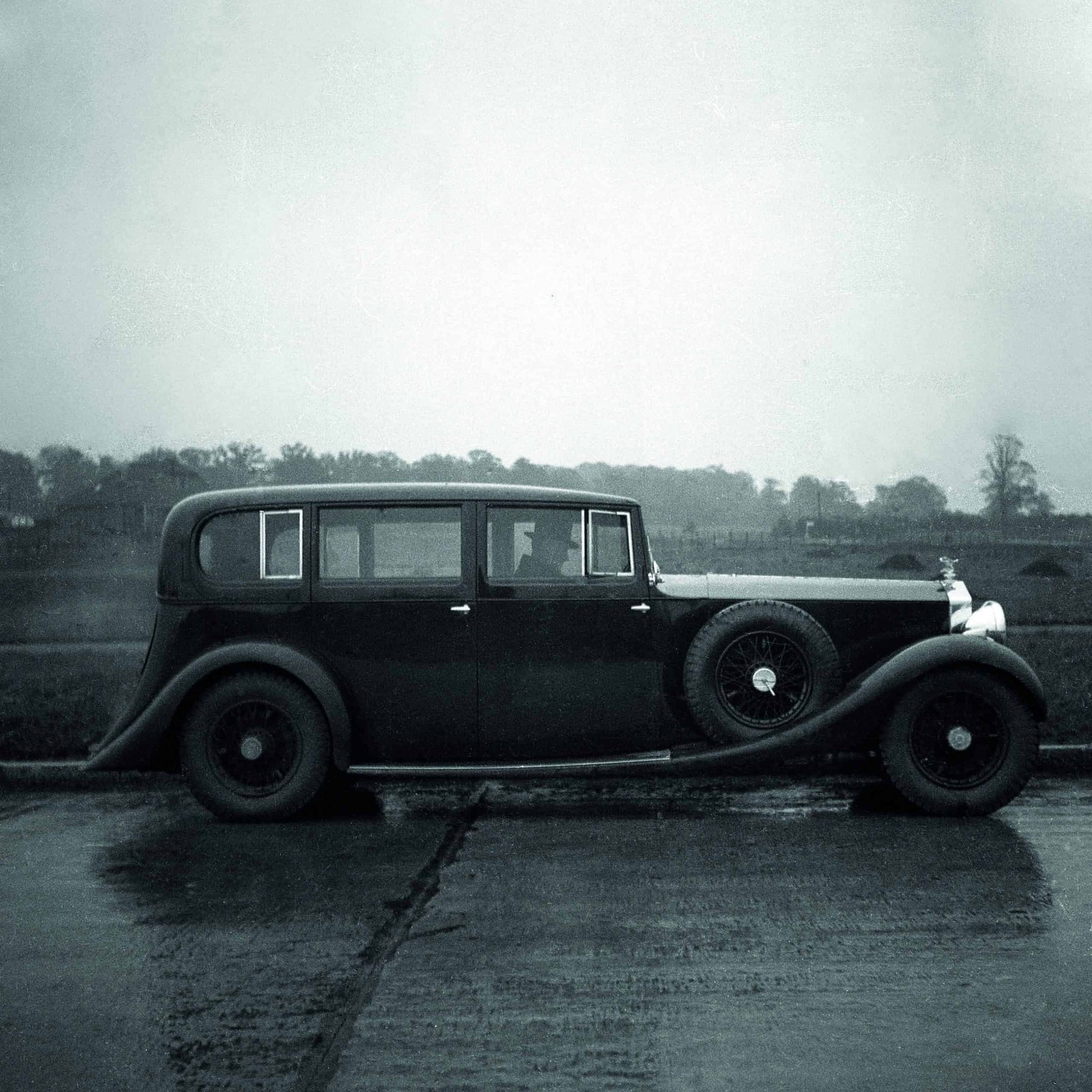 A boldly innovative black and white photo of a car parked in the rain, capturing the spirit of mesmerizing contrasts.