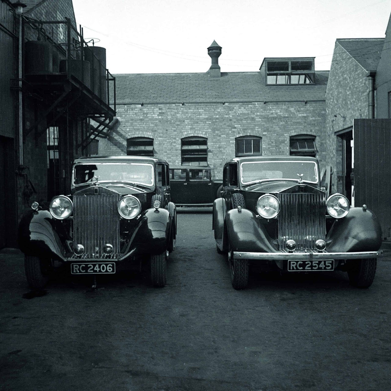 A bold black and white photo of two innovative cars parked in front of a building.