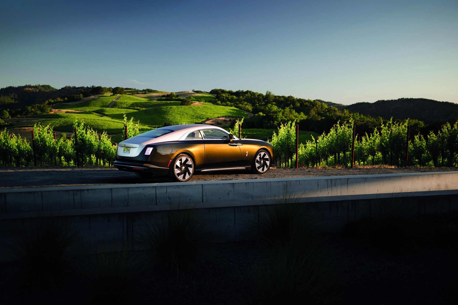 The Rolls Royce Phantom Concept is rising down a road in a vineyard.
