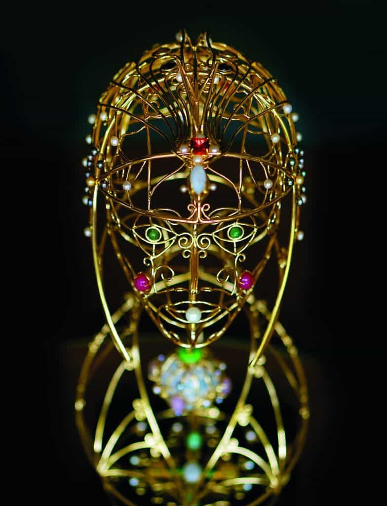 A Bejewelled gold sculpture of a woman's head performing a balancing act.