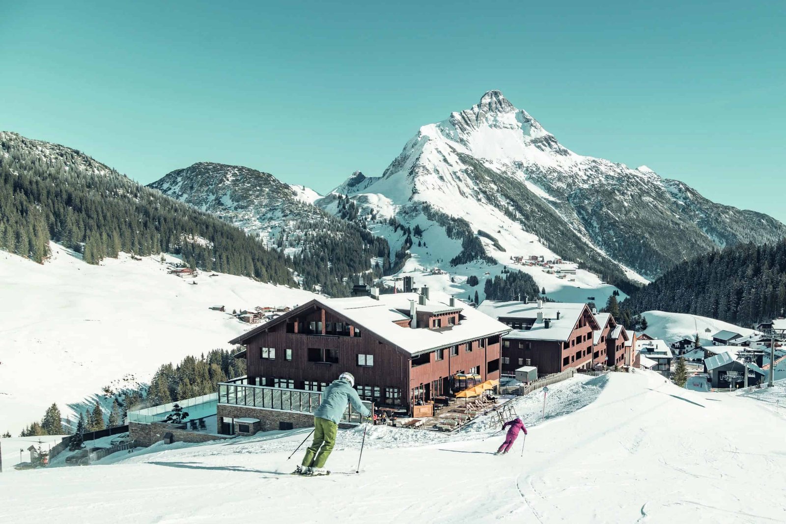 A group of people enjoying the winter season by skiing down a snowy slope with a majestic mountain in the background.