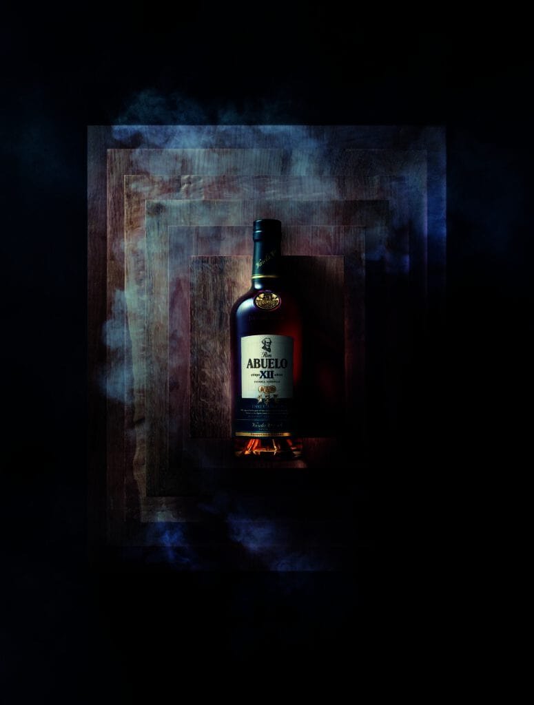 A bottle of whisky sitting on top of a square box, perfect for your next rum punch.