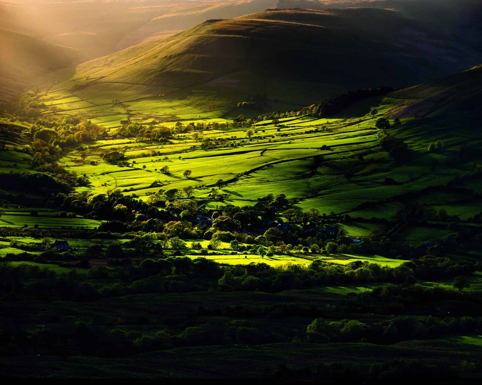 The sun is shining on a peak of green perfection in the valley.
