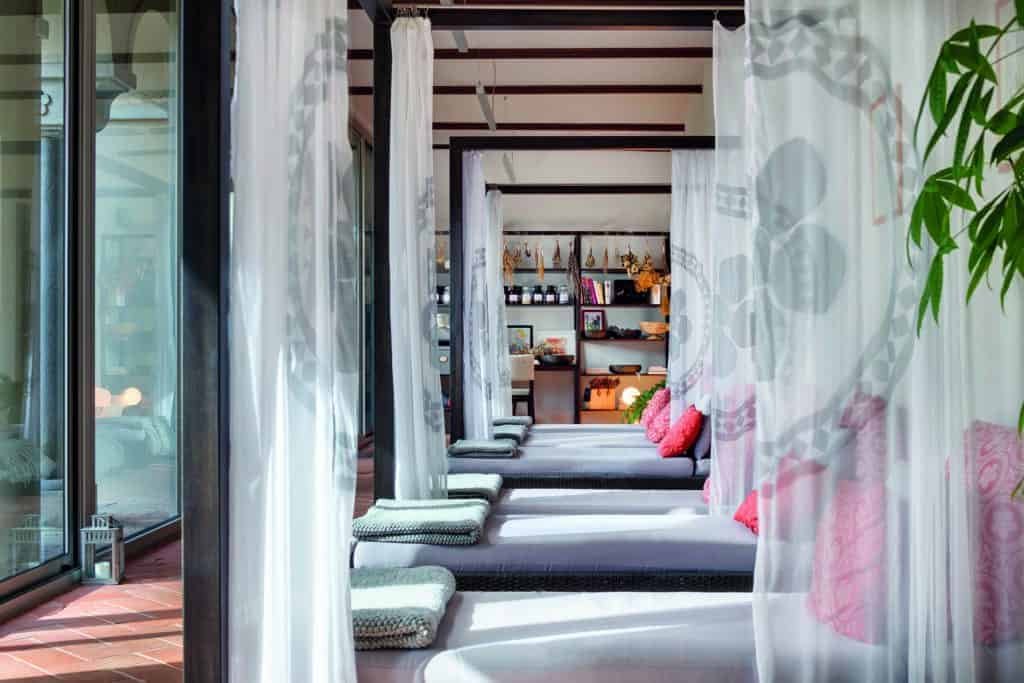 A row of beds in a room with curtains, providing a touch of luxury.