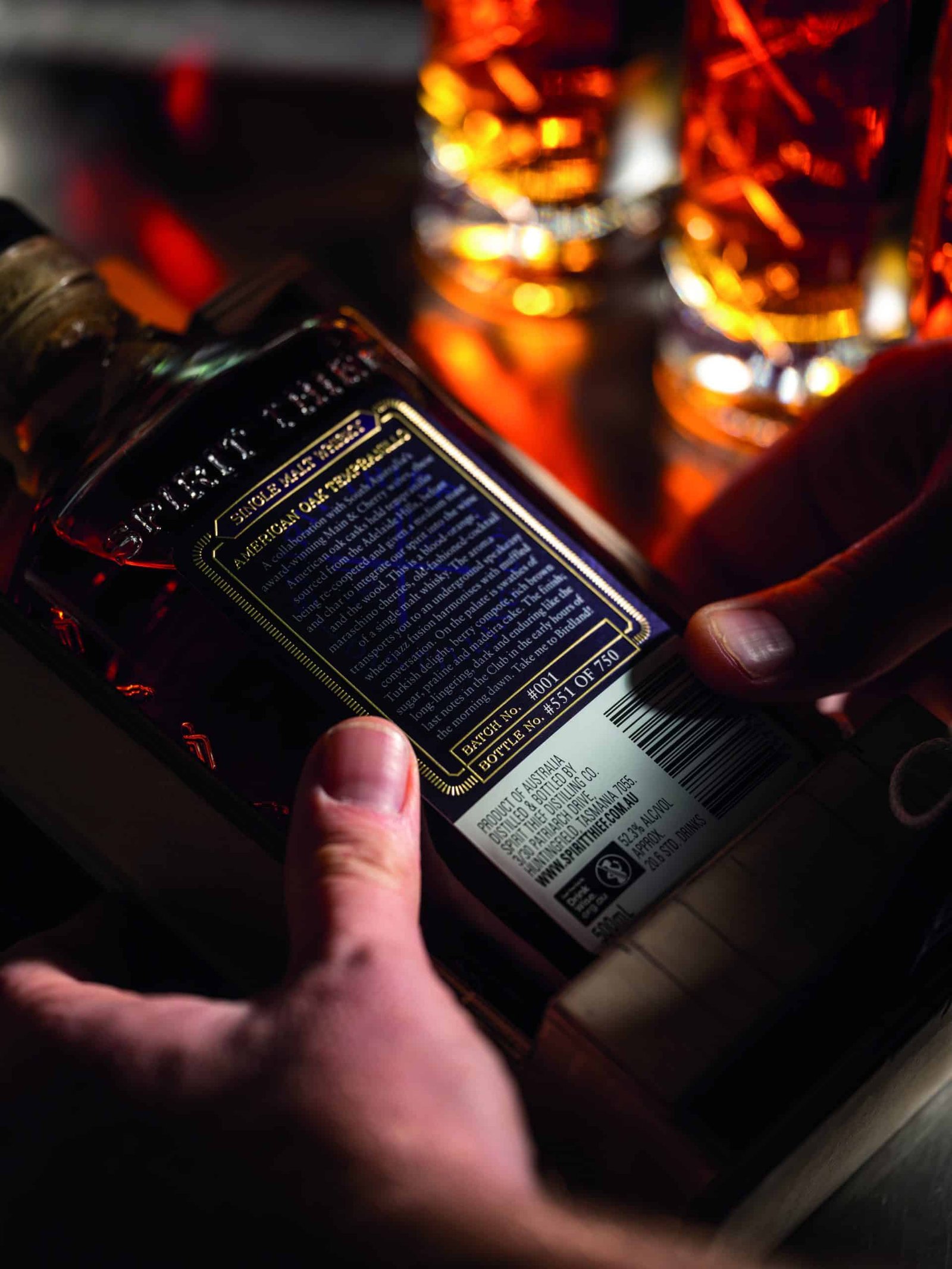 A person holding a bottle of grain whiskey.