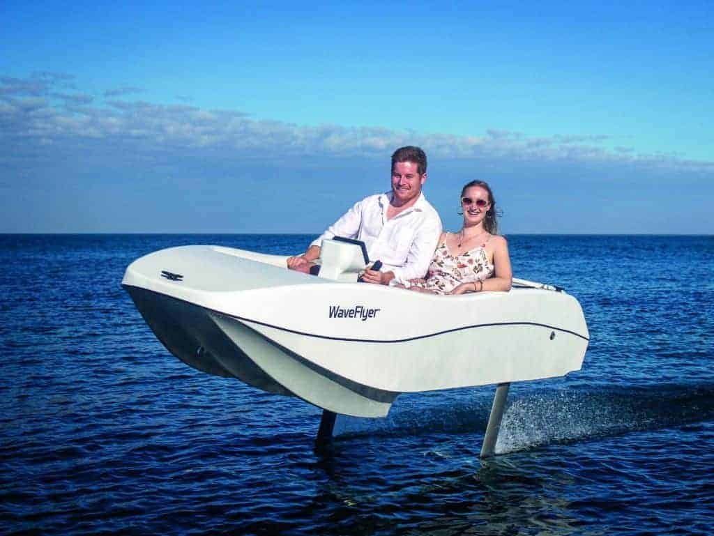 A man and woman riding a motor boat a cut above the ocean.