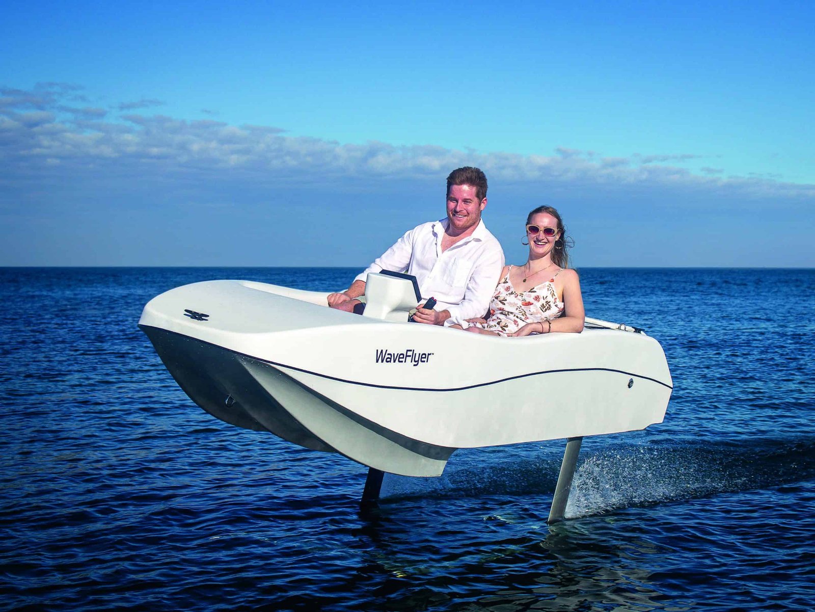 A man and woman riding a motor boat a cut above the ocean.