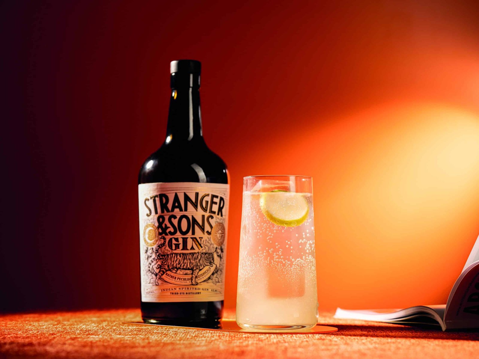 On a table, an intriguing bottle of stranger's bourbon is placed beside a book.