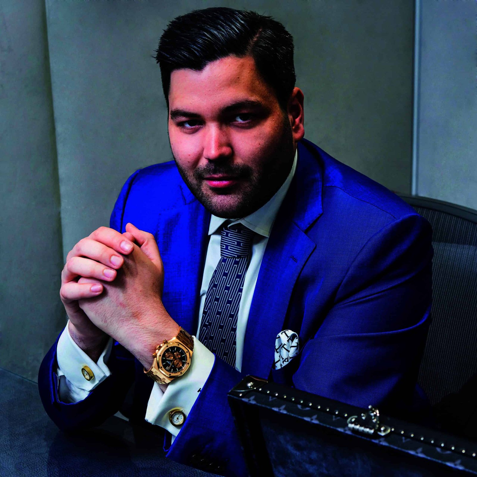 A man in a blue suit sitting at a desk for an hour.