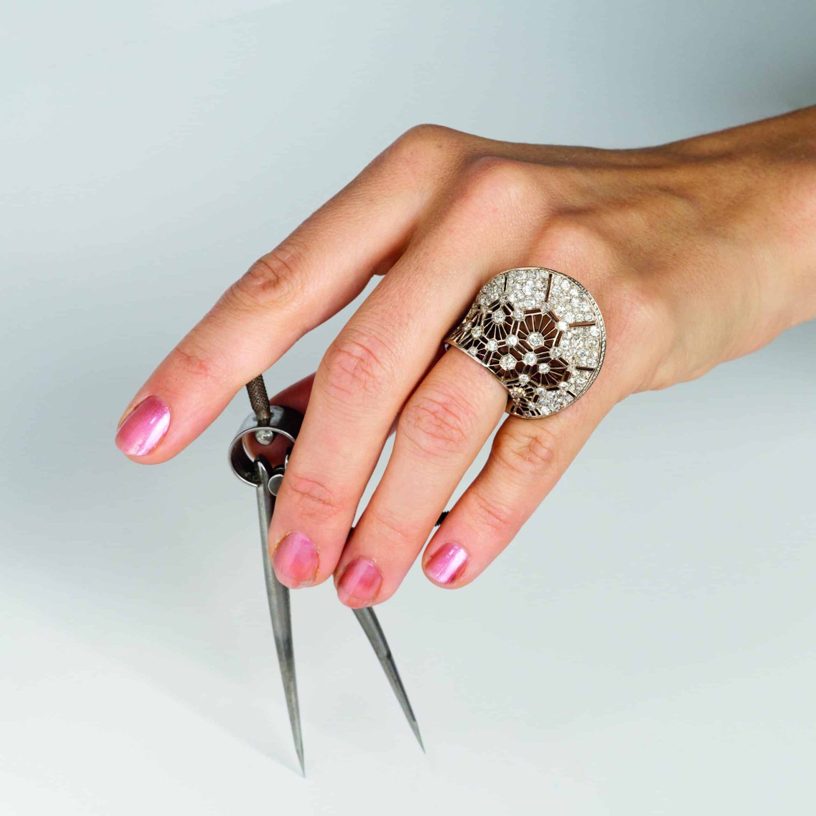 An artistically captured image of a woman's hand delicately holding a pair of scissors.