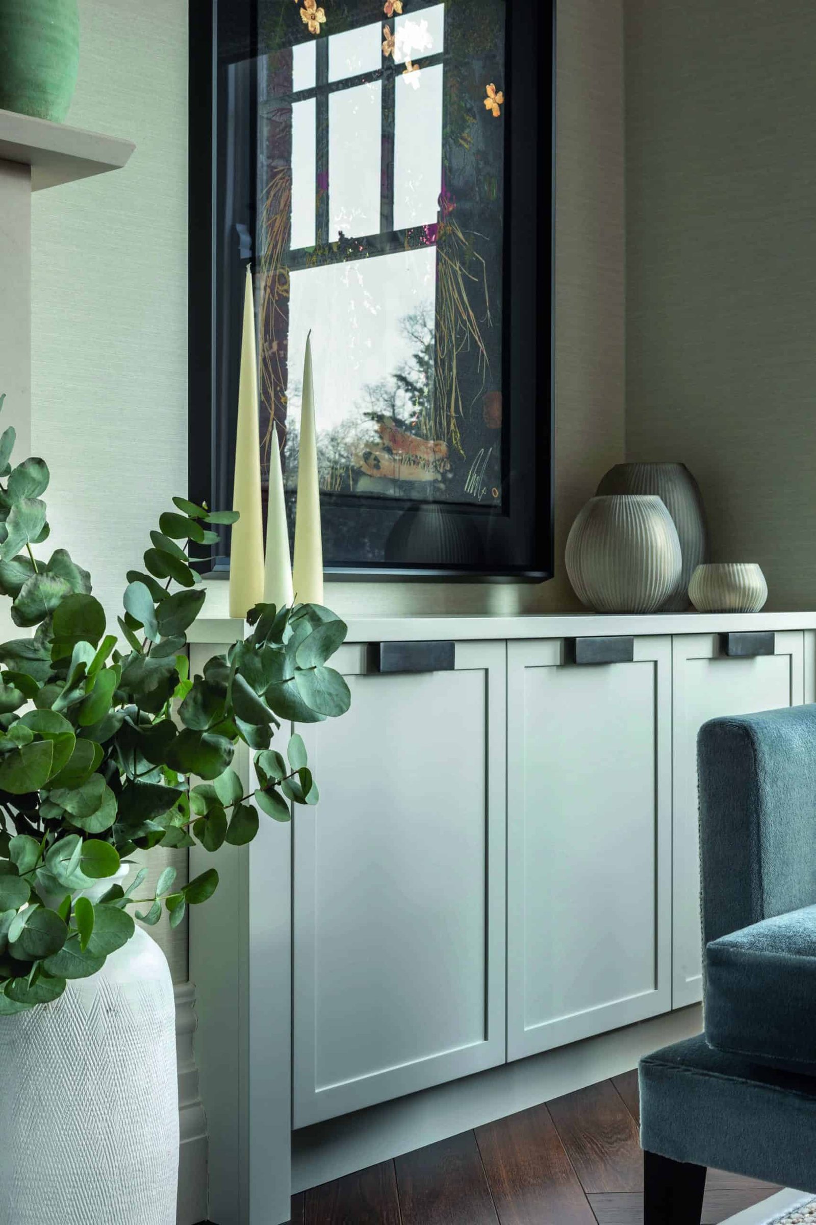 A living room with a bold blue chair and a potted plant.