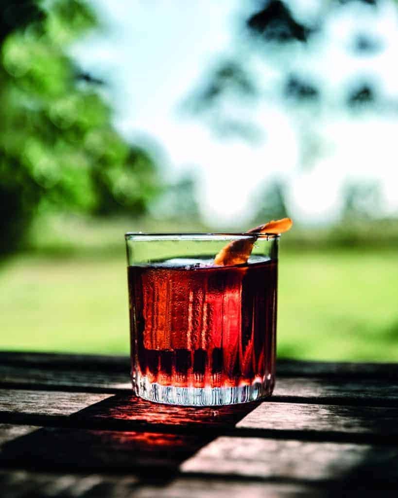 A glass of red liquid sitting on a wooden table, connecting nature.