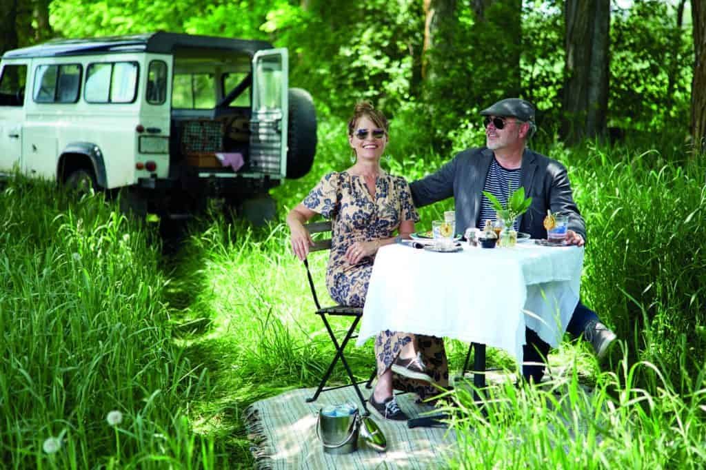 A man and woman connecting at a table in nature.